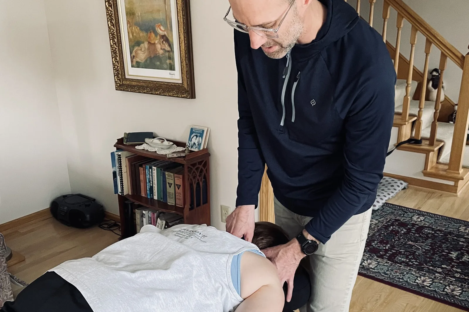 Dr. Travis Nichols treating a client on a portable table in her living room