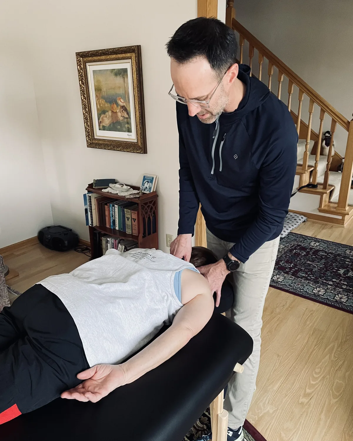 Dr. Travis Nichols treating a client's neck on a portable table in the client's living room